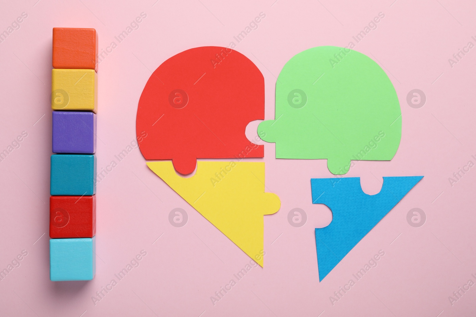 Photo of Colorful cubes and heart made of puzzle pieces on pink background, flat lay