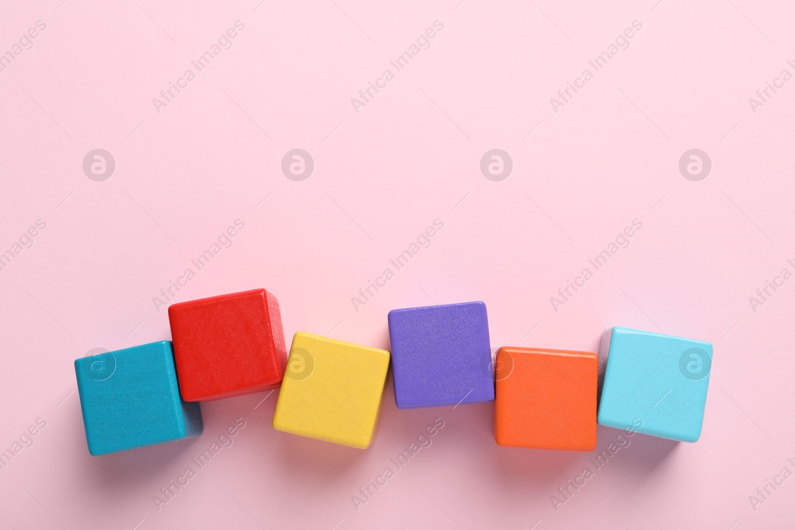 Photo of Colorful cubes on pink background, flat lay. Space for text