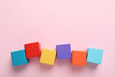 Photo of Colorful cubes on pink background, flat lay. Space for text