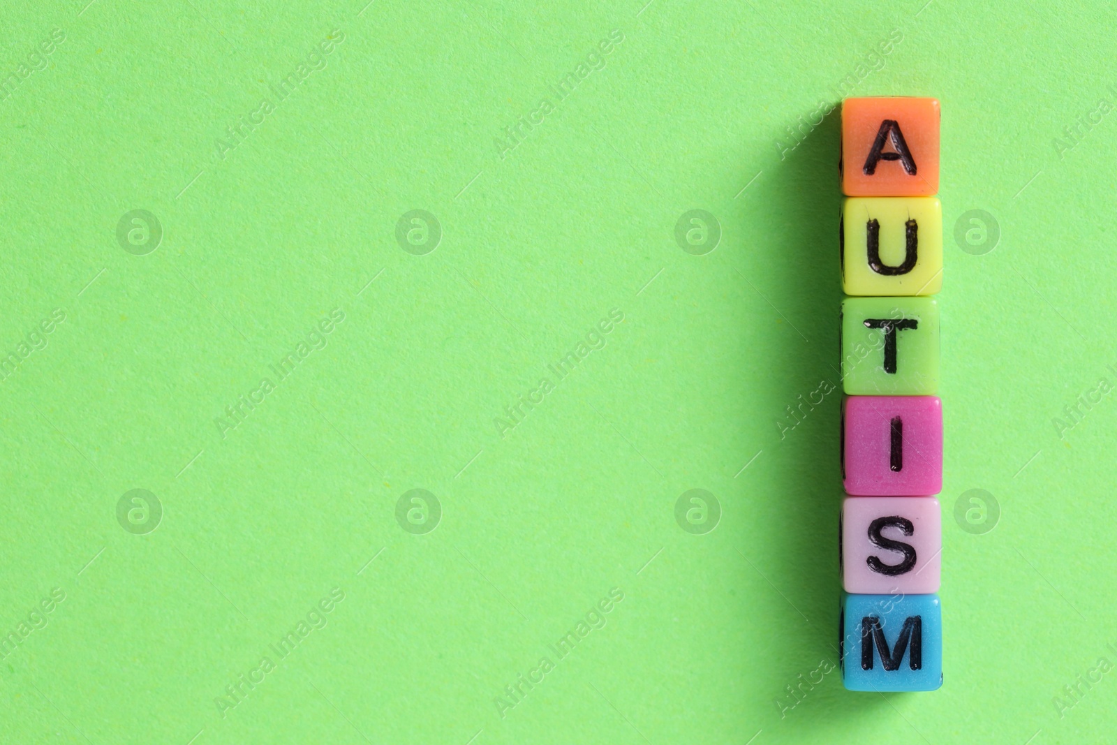 Photo of Word Autism made with colorful cubes on green background, flat lay. Space for text