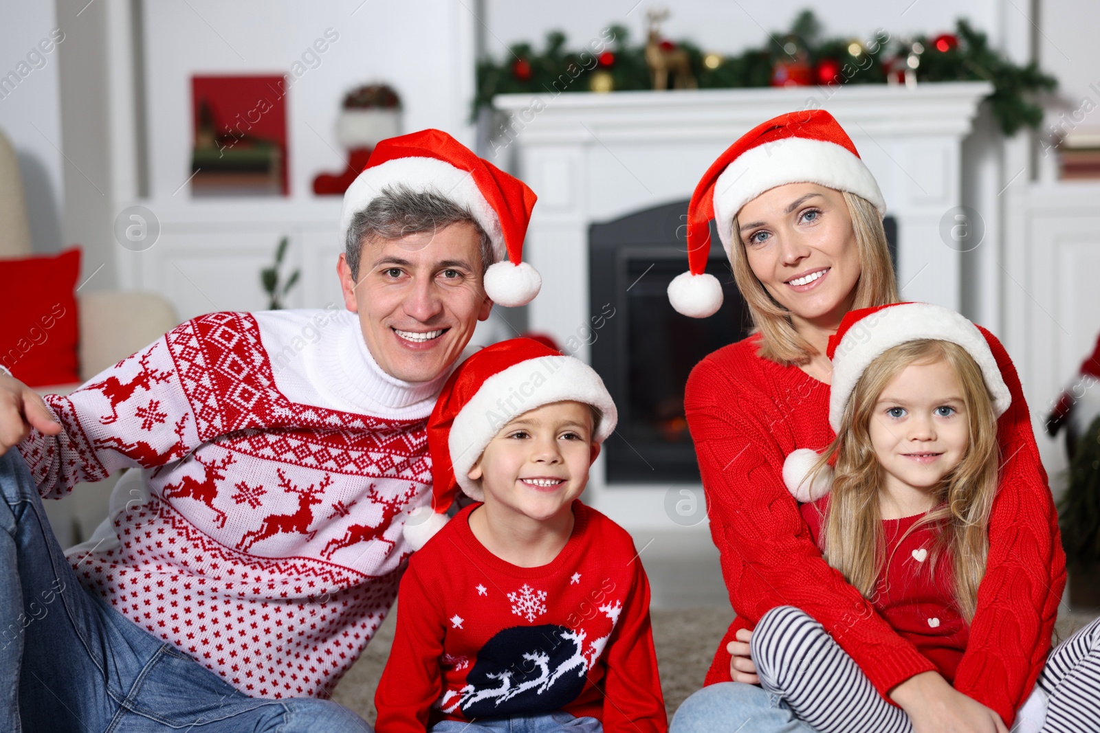 Photo of Lovely family in Christmas sweaters and Santa hats at home