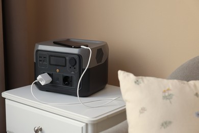 Photo of Smartphone charging from portable power station on nightstand indoors