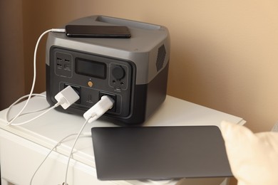 Photo of Devices charging from portable power station on nightstand indoors