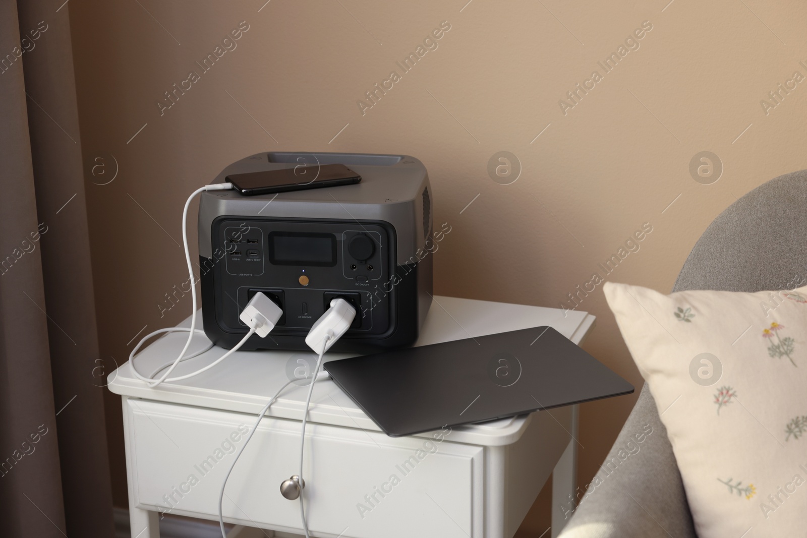 Photo of Devices charging from portable power station on nightstand indoors