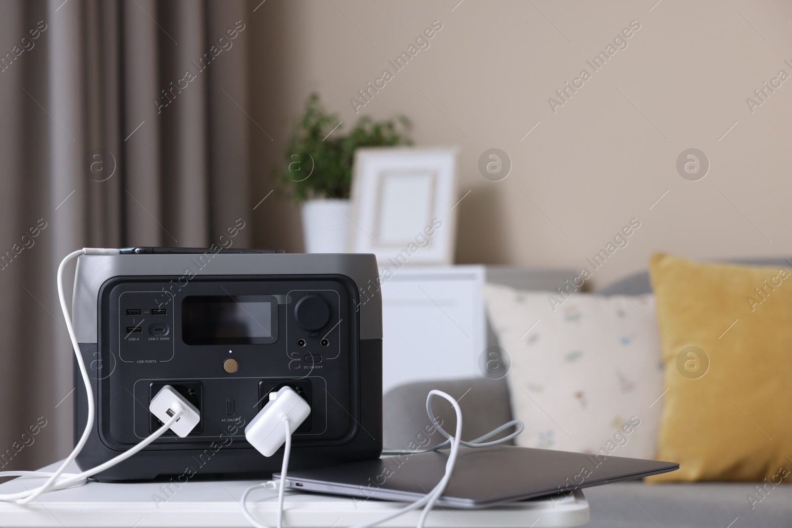 Photo of Devices charging from portable power station on white table indoors