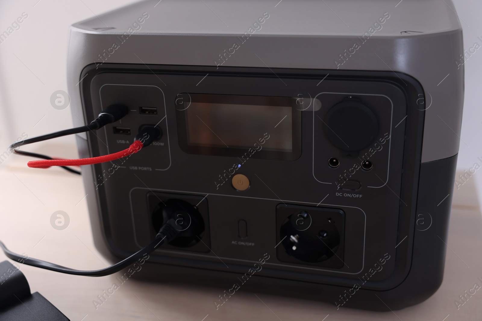 Photo of Portable power station with cables on table indoors, closeup