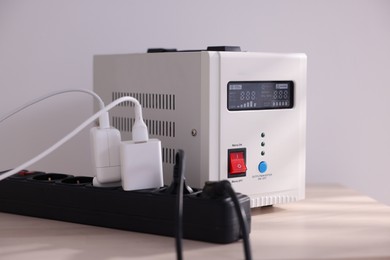 Photo of Portable power station and multi-socket extension board with chargers on table indoors