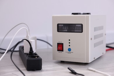 Photo of Portable power station and multi-socket extension board with chargers on table indoors