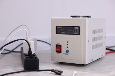 Photo of Portable power station and multi-socket extension board with chargers on table indoors