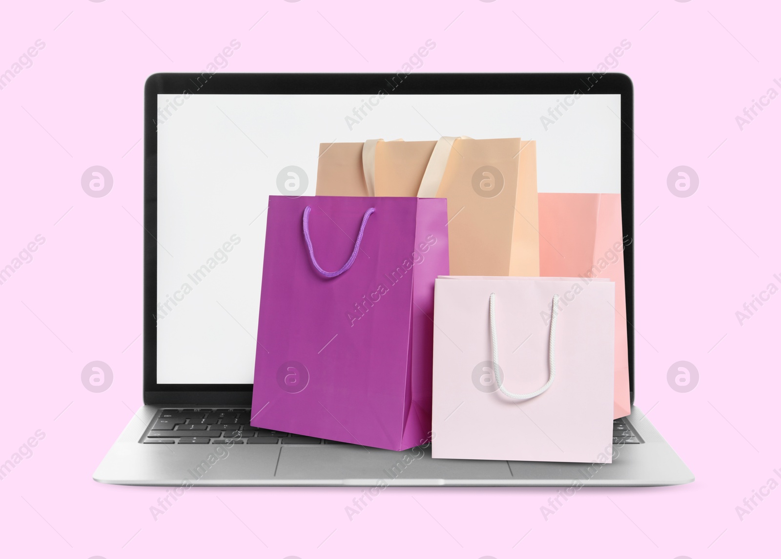 Image of Laptop with shopping bags on pink background. Concept of online shopping, purchase via internet