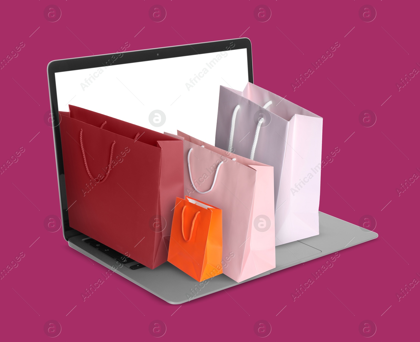 Image of Laptop with shopping bags on violet red background. Concept of online shopping, purchase via internet