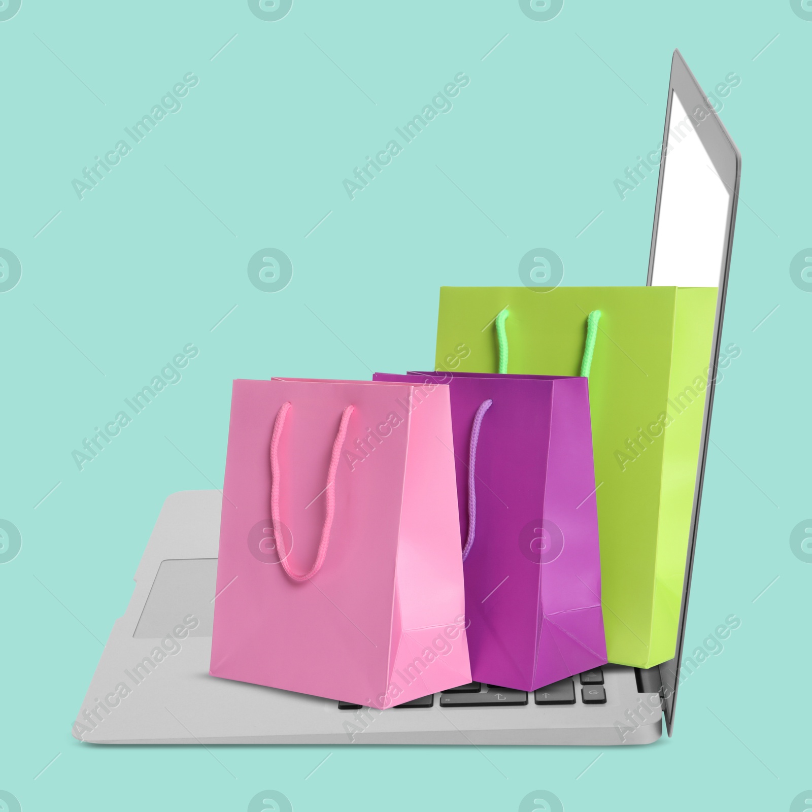 Image of Laptop with shopping bags on turquoise background. Concept of online shopping, purchase via internet