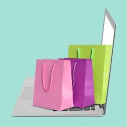 Image of Laptop with shopping bags on turquoise background. Concept of online shopping, purchase via internet