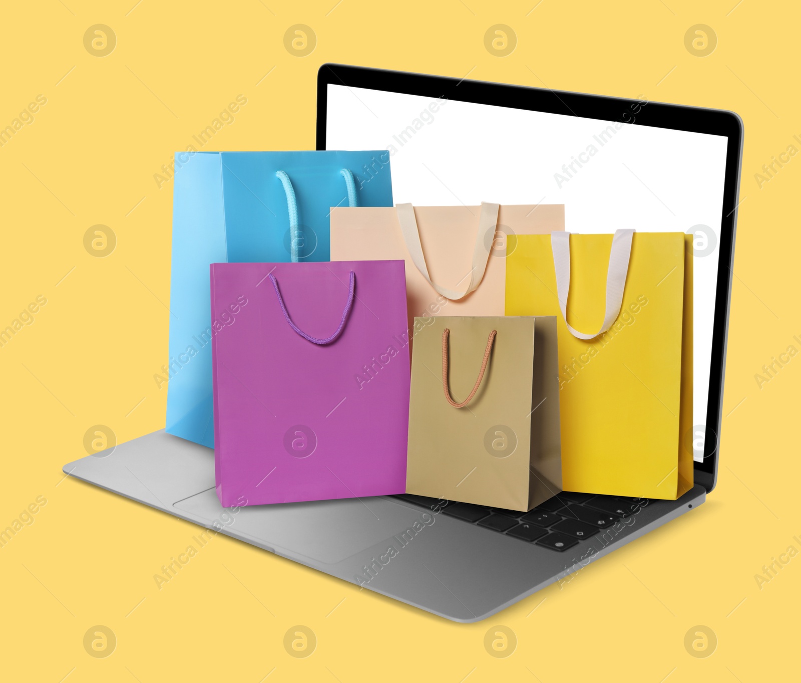 Image of Laptop with shopping bags on yellow background. Concept of online shopping, purchase via internet