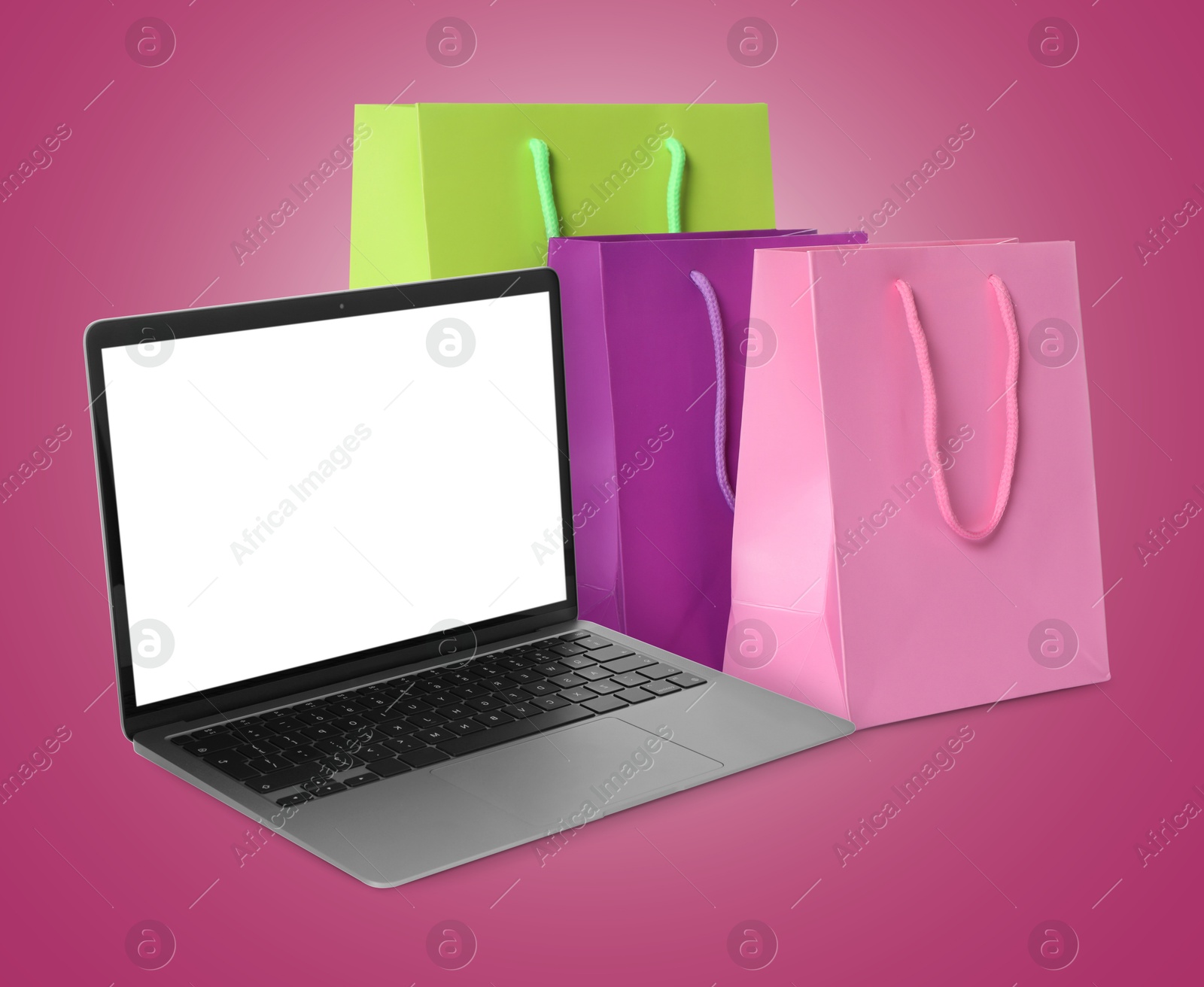 Image of Laptop and shopping bags on violet red background. Concept of online shopping, purchase via internet