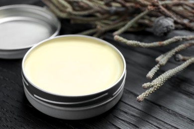 Photo of Natural solid perfume and plant on black wooden table, closeup