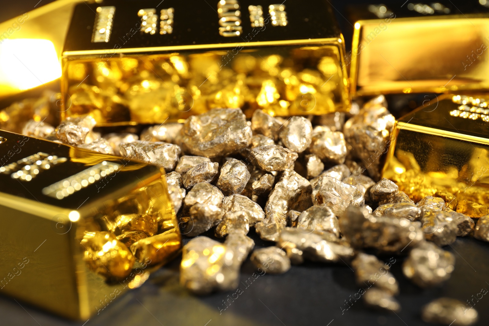 Photo of Gold nuggets and bars on black table, closeup