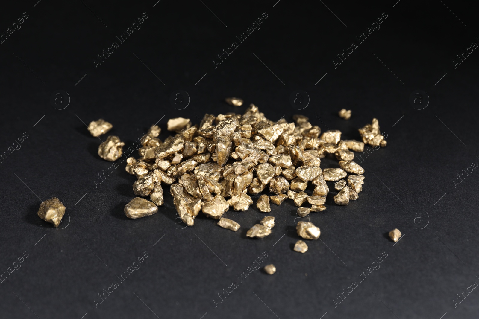 Photo of Shiny gold nuggets on black table, closeup