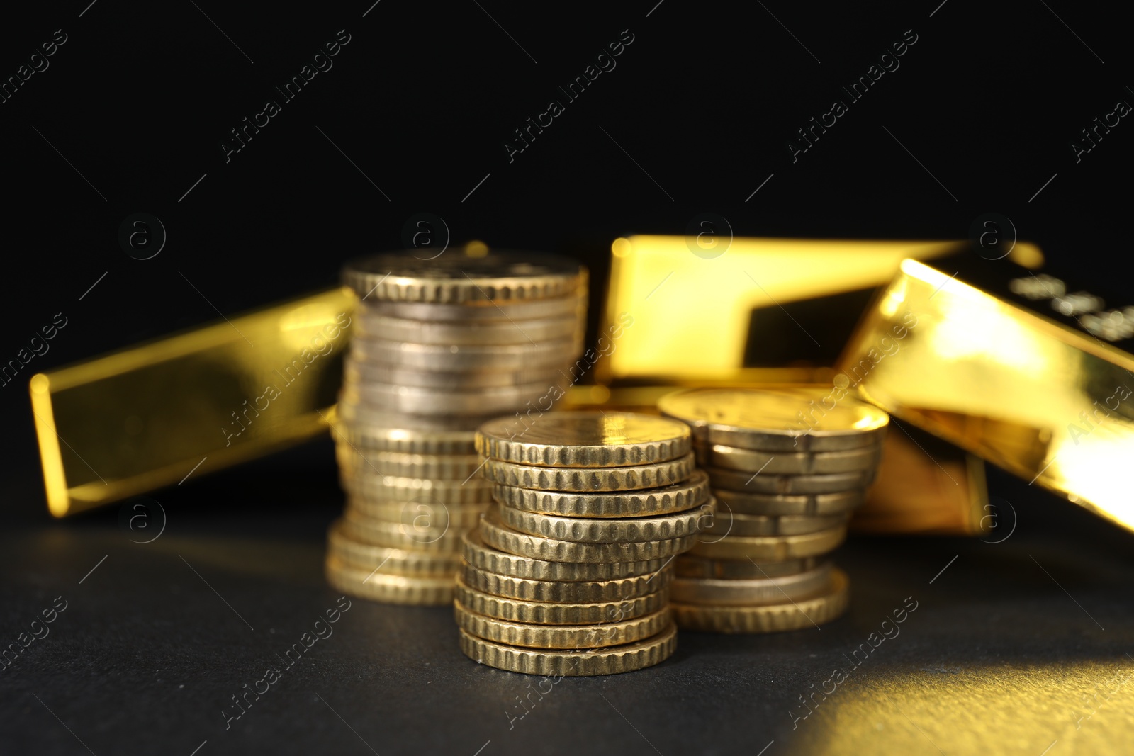 Photo of Gold bars and coins on black table, closeup