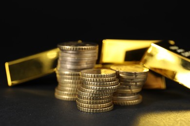 Photo of Gold bars and coins on black table, closeup