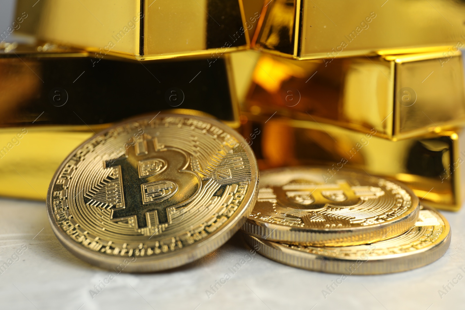 Photo of Gold bars and coins on grey table, closeup