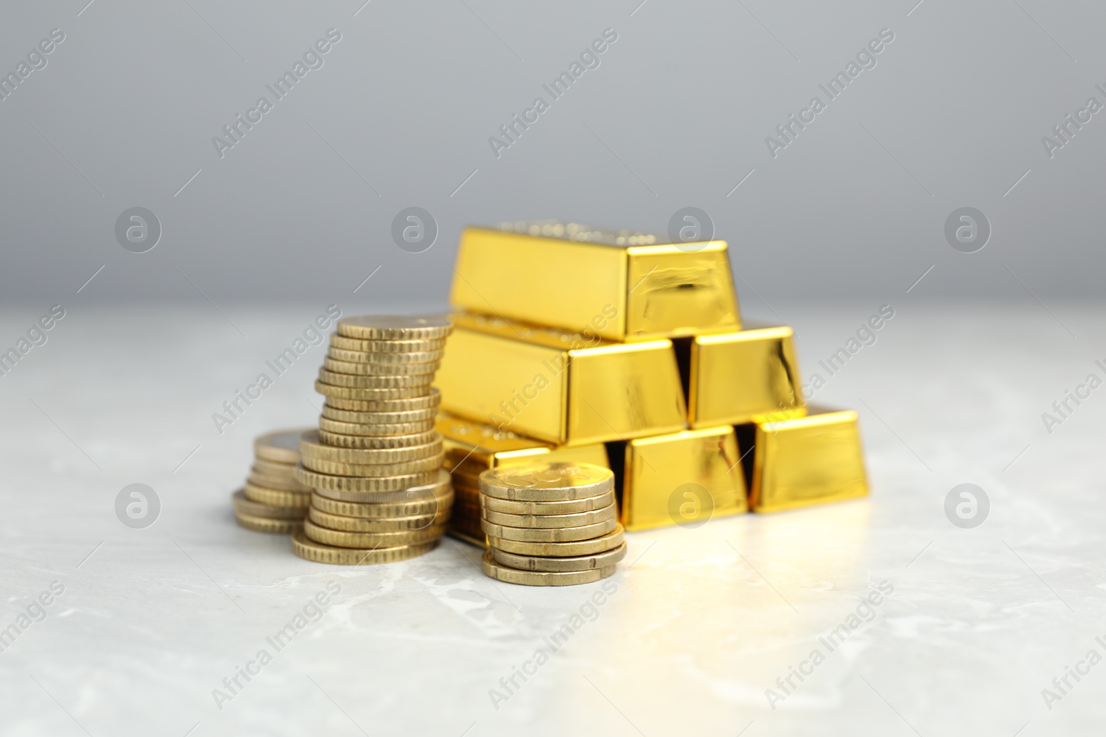 Photo of Gold bars and coins on grey marble table, closeup