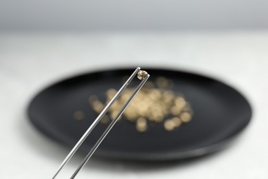 Photo of Tweezers with gold nugget against blurred background, closeup