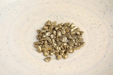 Photo of Many shiny gold nuggets in bowl, closeup