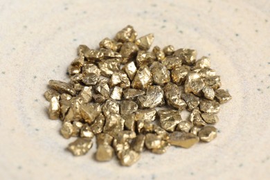 Photo of Many shiny gold nuggets in bowl, closeup