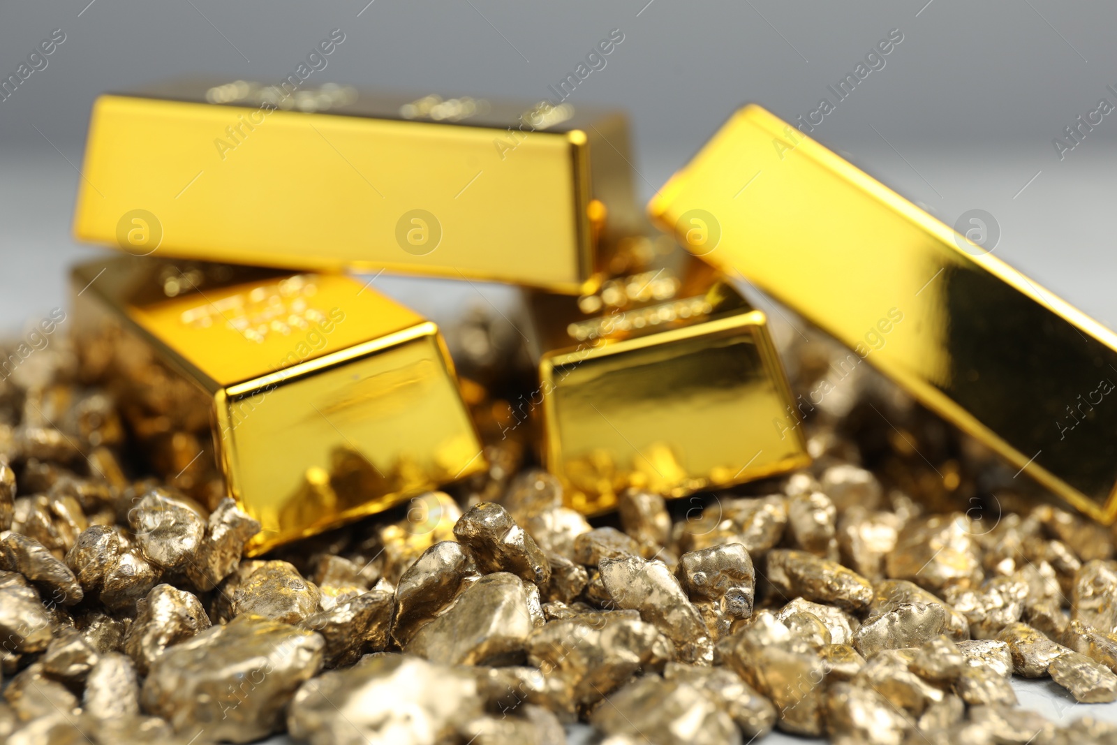 Photo of Gold nuggets and bars against blurred background, closeup