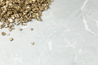 Photo of Gold nuggets on grey marble table, closeup. Space for text