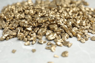 Photo of Gold nuggets on grey marble table, closeup