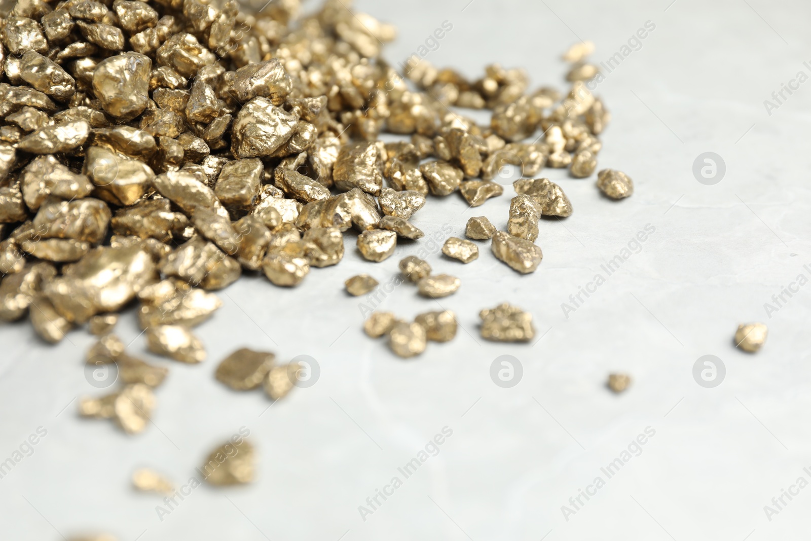 Photo of Gold nuggets on grey marble table, closeup. Space for text