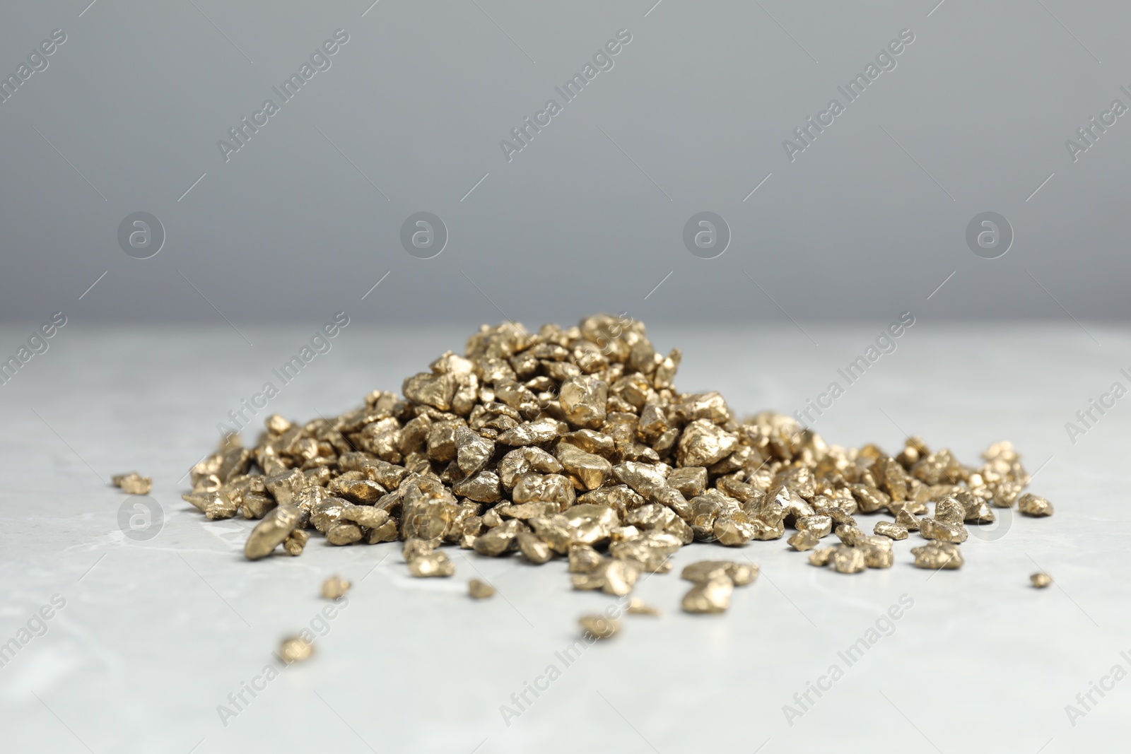 Photo of Gold nuggets on grey marble table, closeup