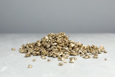 Photo of Gold nuggets on grey marble table, closeup