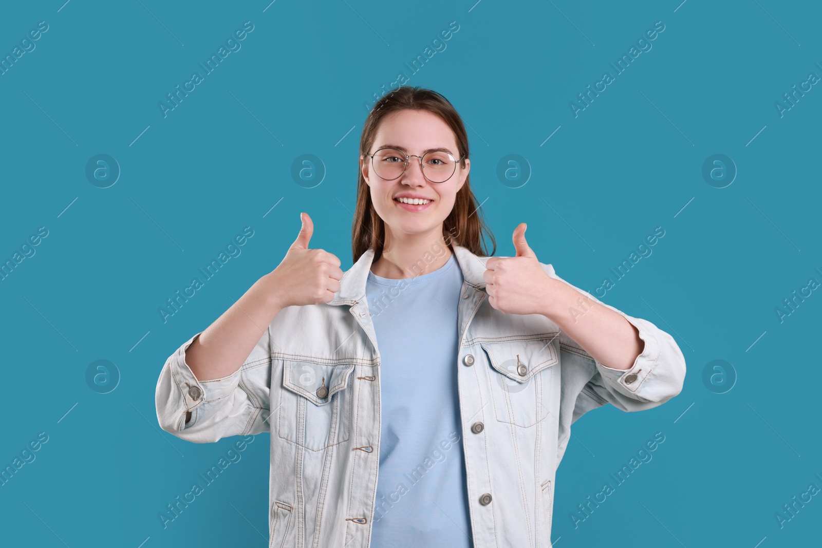 Photo of Happy woman showing thumbs up on light blue background. Like gesture