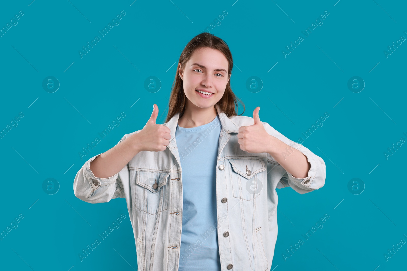 Photo of Happy woman showing thumbs up on light blue background. Like gesture