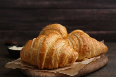 Photo of Tasty fresh croissants on wooden table, closeup