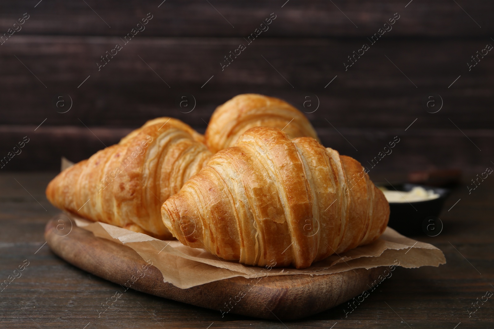 Photo of Tasty fresh croissants on wooden table, closeup