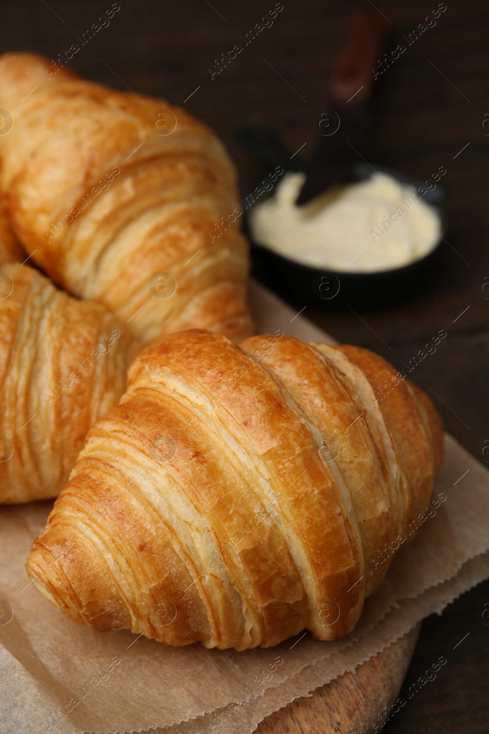 Photo of Tasty fresh croissants served with butter on wooden table, closeup