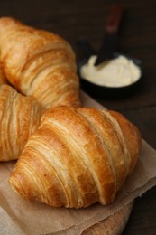 Photo of Tasty fresh croissants served with butter on wooden table, closeup