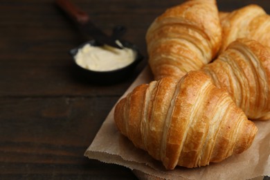 Photo of Tasty fresh croissants served with butter on wooden table, closeup. Space for text