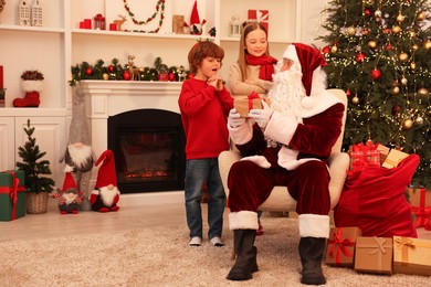 Christmas celebration. Santa Claus giving gift box to kids at home