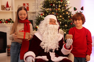 Photo of Christmas celebration. Santa Claus and kids with gift boxes at home