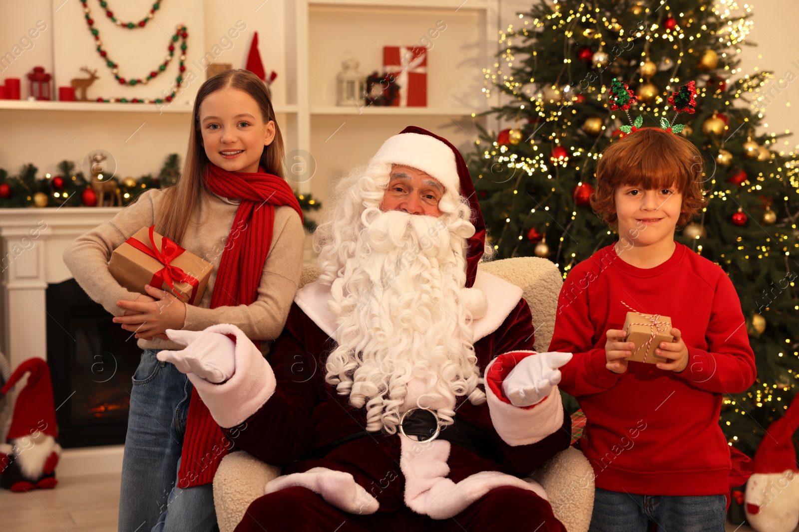 Photo of Christmas celebration. Santa Claus and kids with gift boxes at home