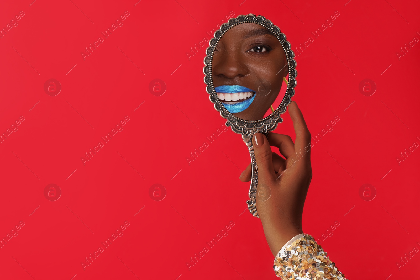 Image of Beautiful woman looking in handheld mirror on red background, closeup. Space for text