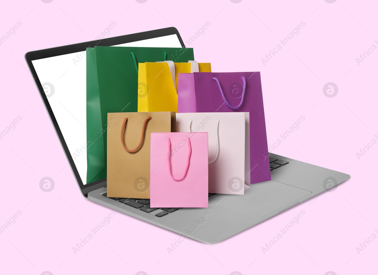 Image of Laptop with shopping bags on pink background. Concept of online shopping, purchase via internet