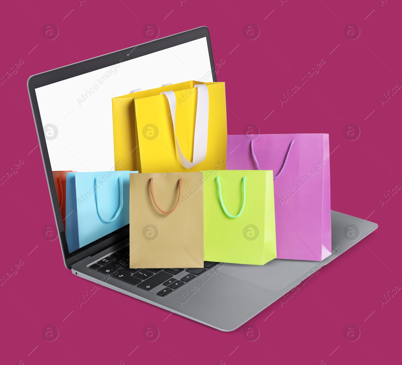 Image of Laptop with shopping bags on violet red background. Concept of online shopping, purchase via internet