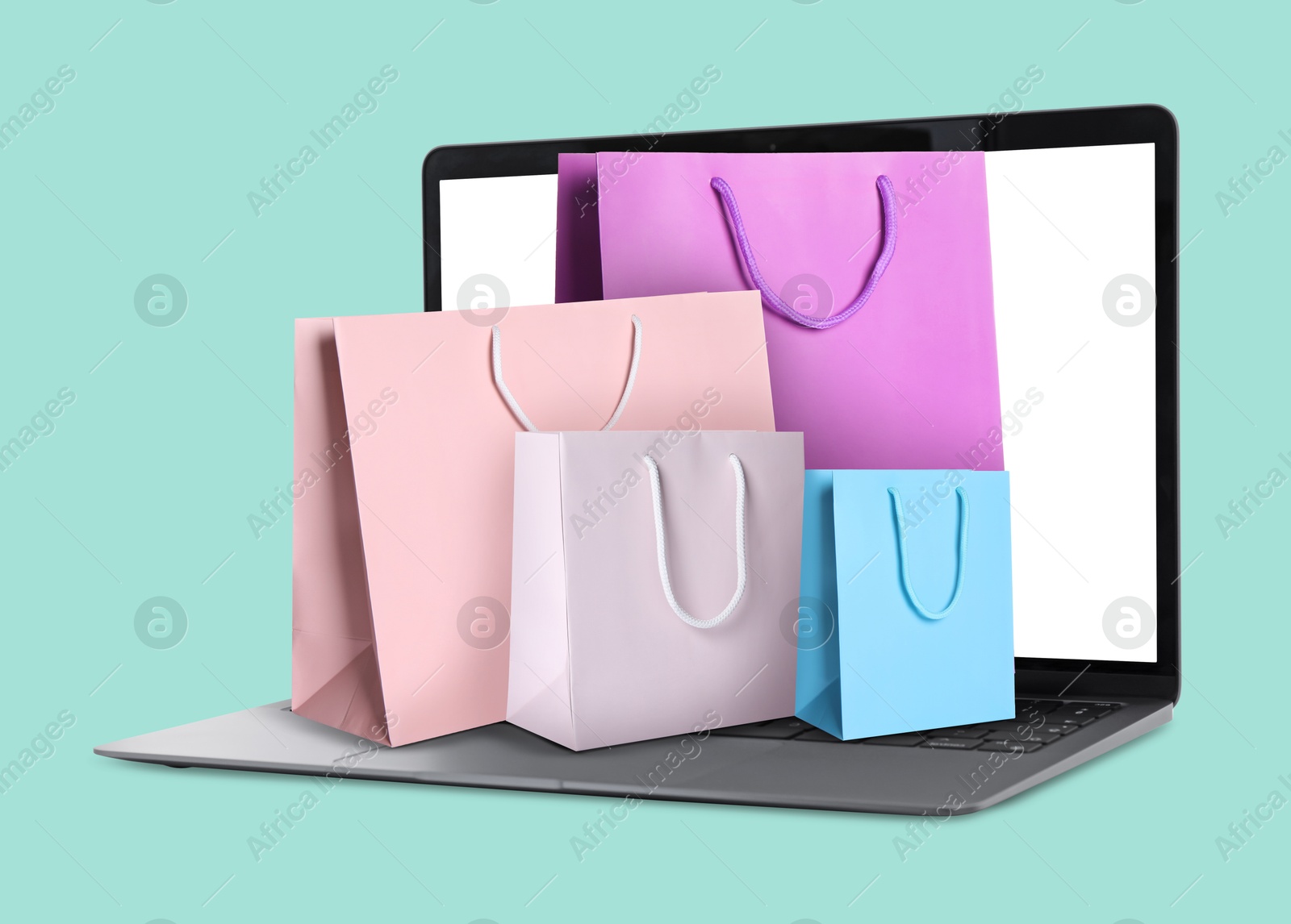 Image of Laptop with shopping bags on turquoise background. Concept of online shopping, purchase via internet