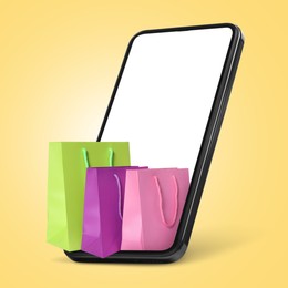 Image of Mobile phone with shopping bags on yellow background. Concept of online shopping, purchase via internet